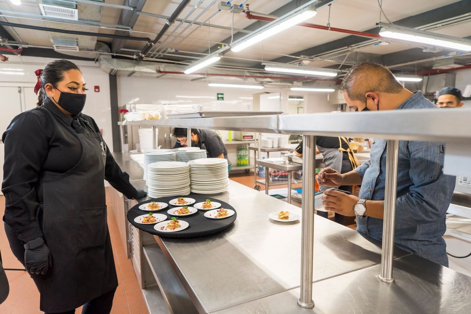 Keukenmedewerkers werken bij de pas met opgemaakte borden
