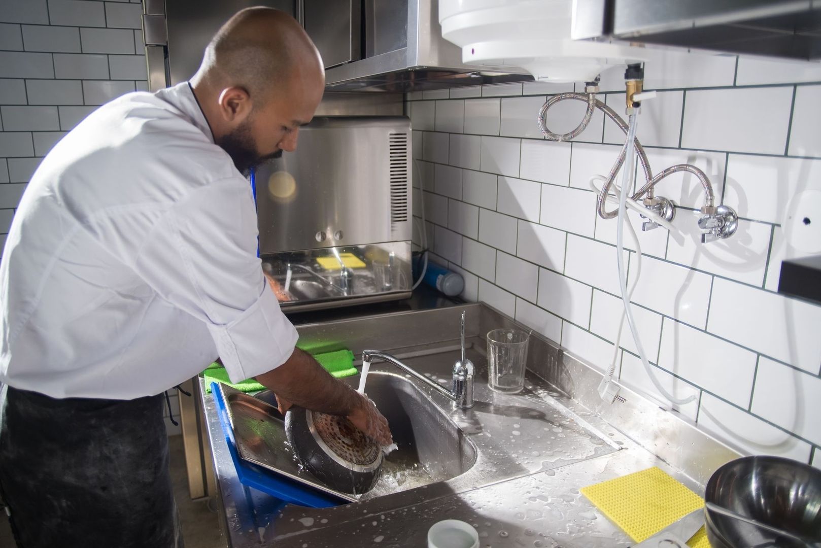 Keukenmedewerker wast servies in een industriële spoelkeuken